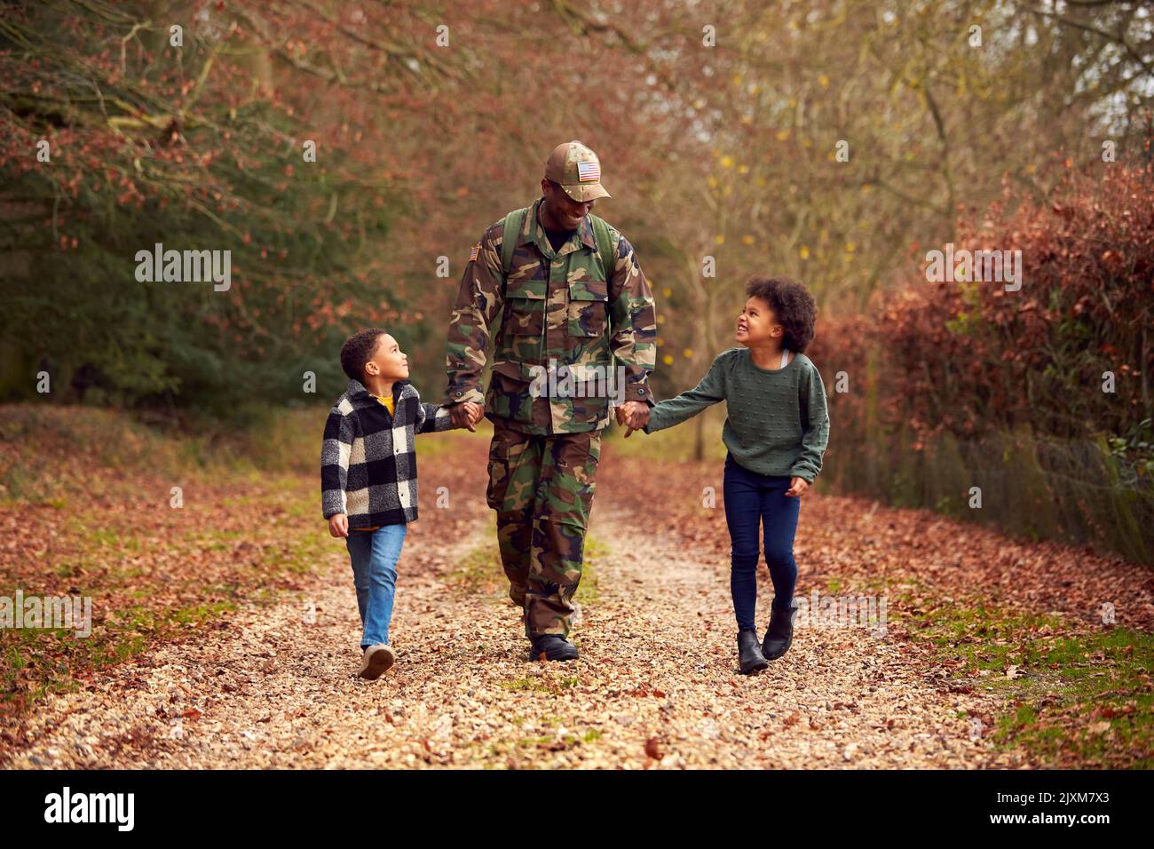 Soldato americano in uniforme ritorno a casa in congedo per la famiglia Holding mani con due bambini Foto Stock