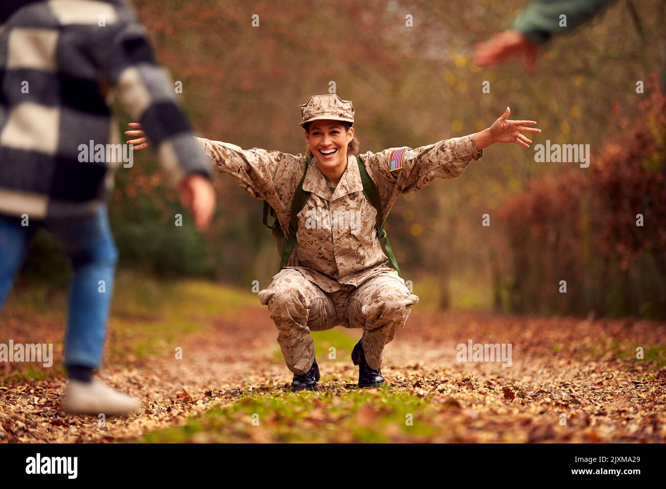 American Female Soldato in uniforme ritorno a casa in congedo alla famiglia salutato da due bambini Foto Stock