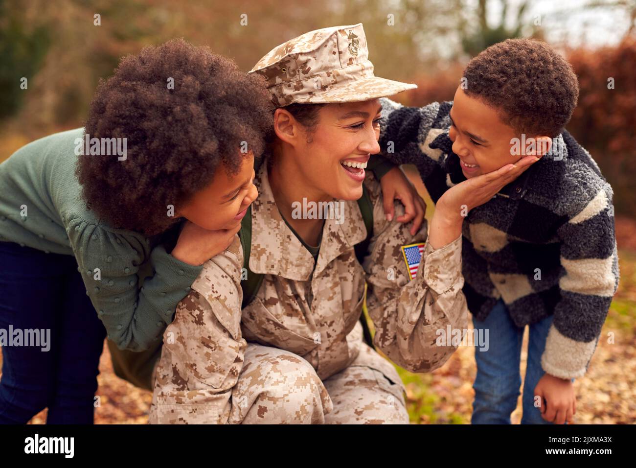 American Female Soldato in uniforme ritorno a casa in congedo alla famiglia salutato da due bambini Foto Stock