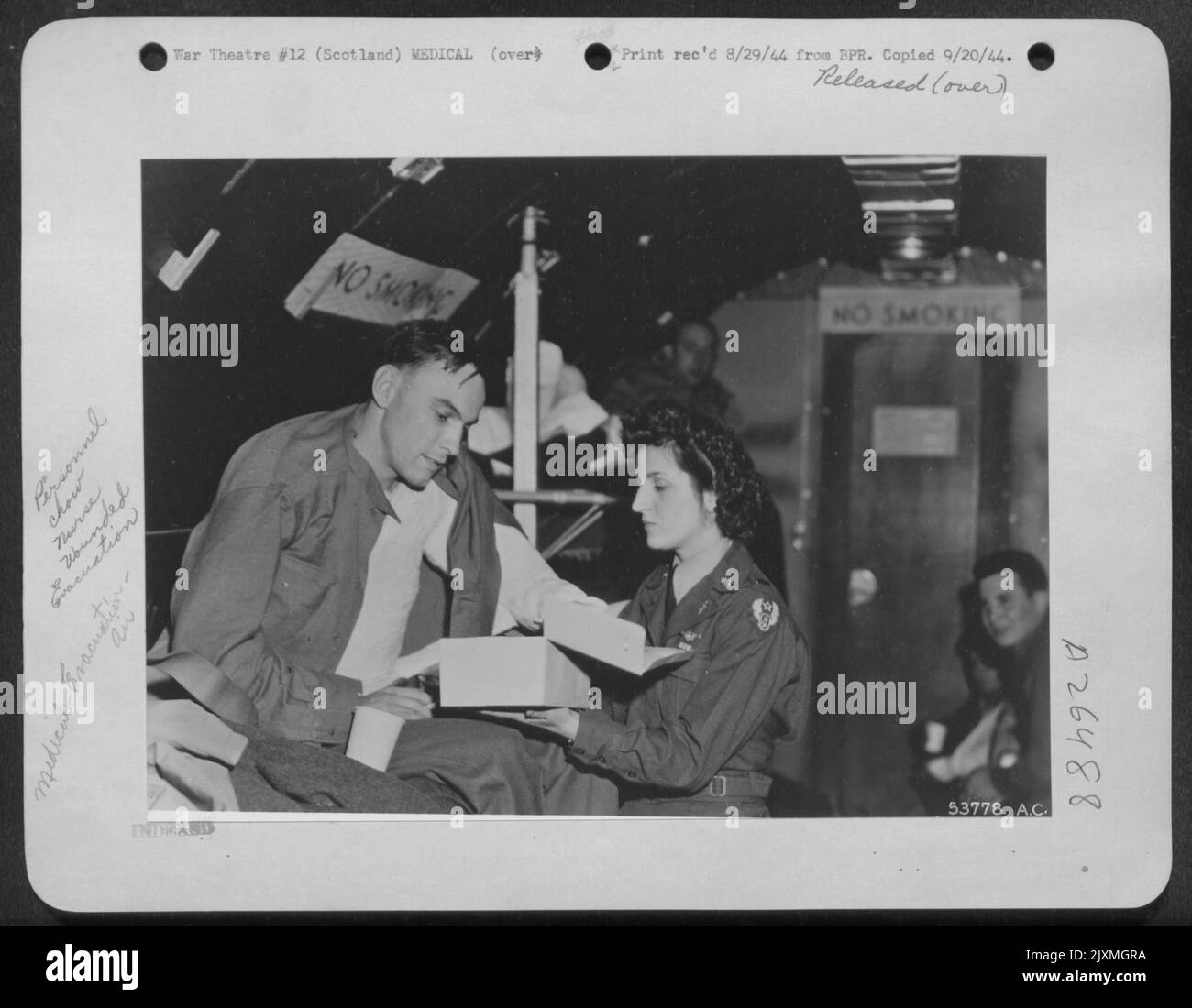 Chow chiamata a bordo di un enorme aereo ATC che porta l'invasione feriti dalla Scozia negli Stati Uniti ha portato Petite 2D Lt. Irene Wendte, infermiera di volo del Wisconsin, al fianco di Seaman 1/C George G. Massing, di St. Louis, Mo., che è stato ferito sulla costa francese. Foto Stock