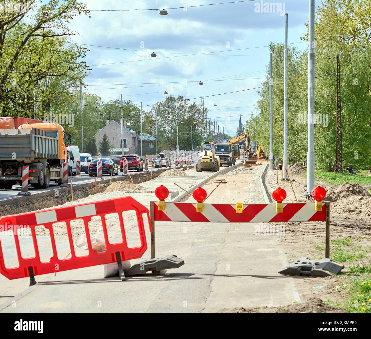 RIGA, LETTONIA - 13 MAGGIO 2022: Blocco delle barriere sulla riparazione stradale. Traffico intenso su via Deglava. Macchine da costruzione accanto. Foto Stock