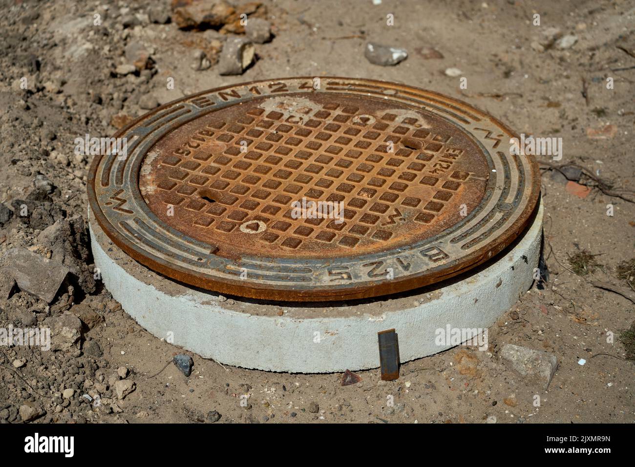 Scolo rotondo e arrugginito del portello della fogna sul cantiere. Foto Stock