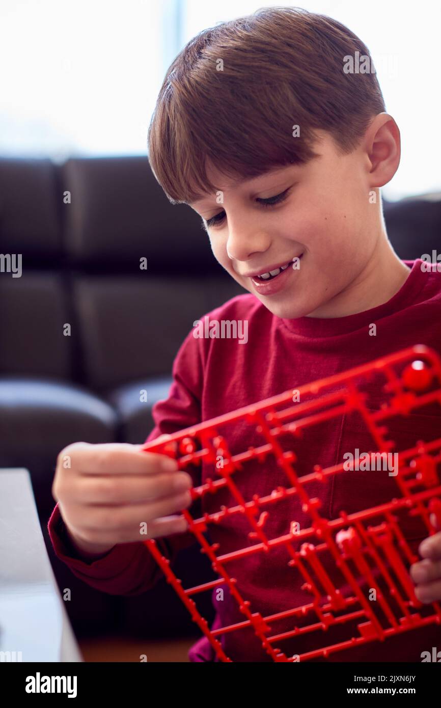 Ragazzo che indossa i pigiami che costruano il braccio robotico del kit di plastica a casa Foto Stock