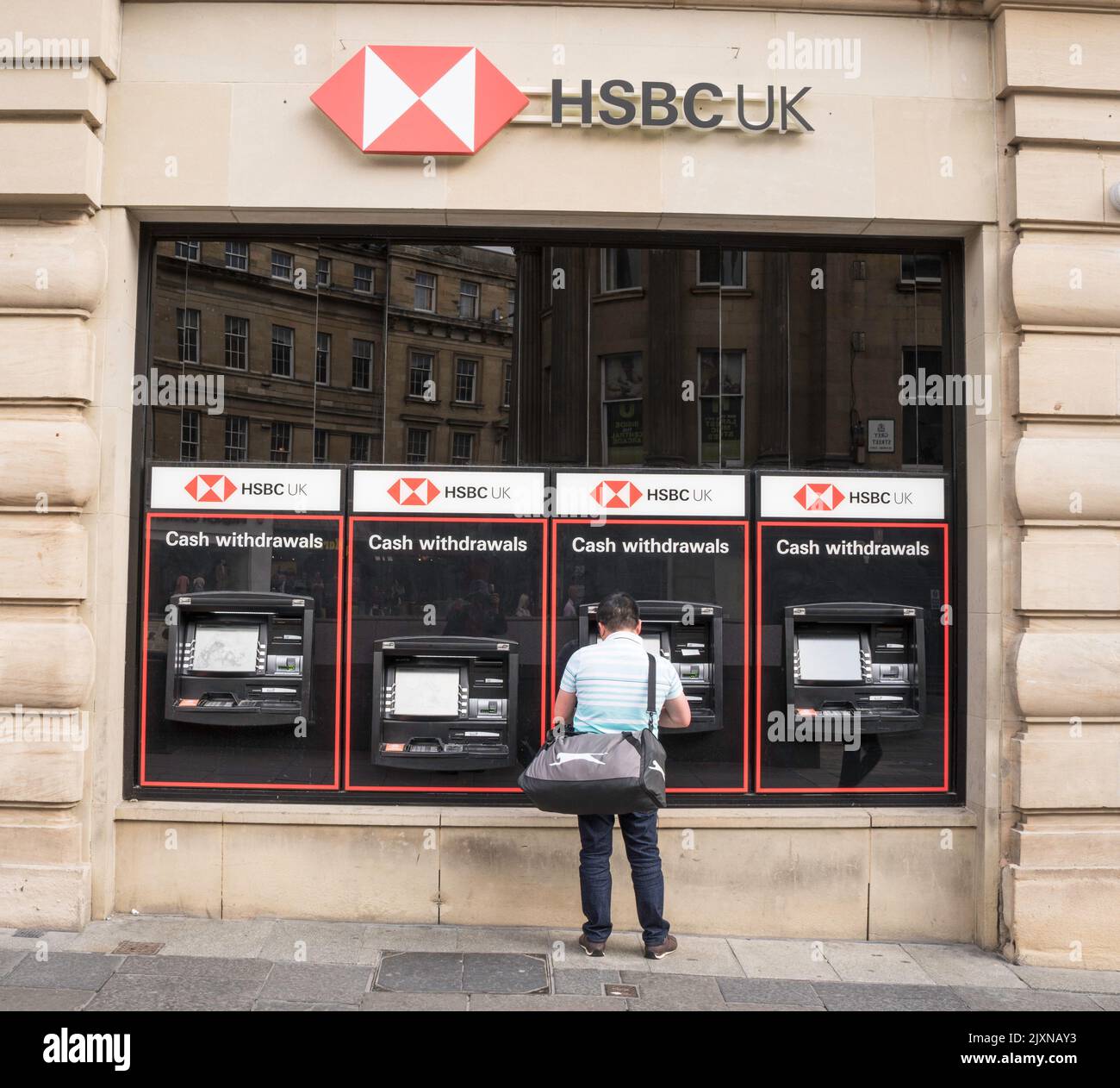 Un uomo ritira denaro da un bancomat HSBC a Newcastle upon Tyne, Inghilterra, Regno Unito Foto Stock
