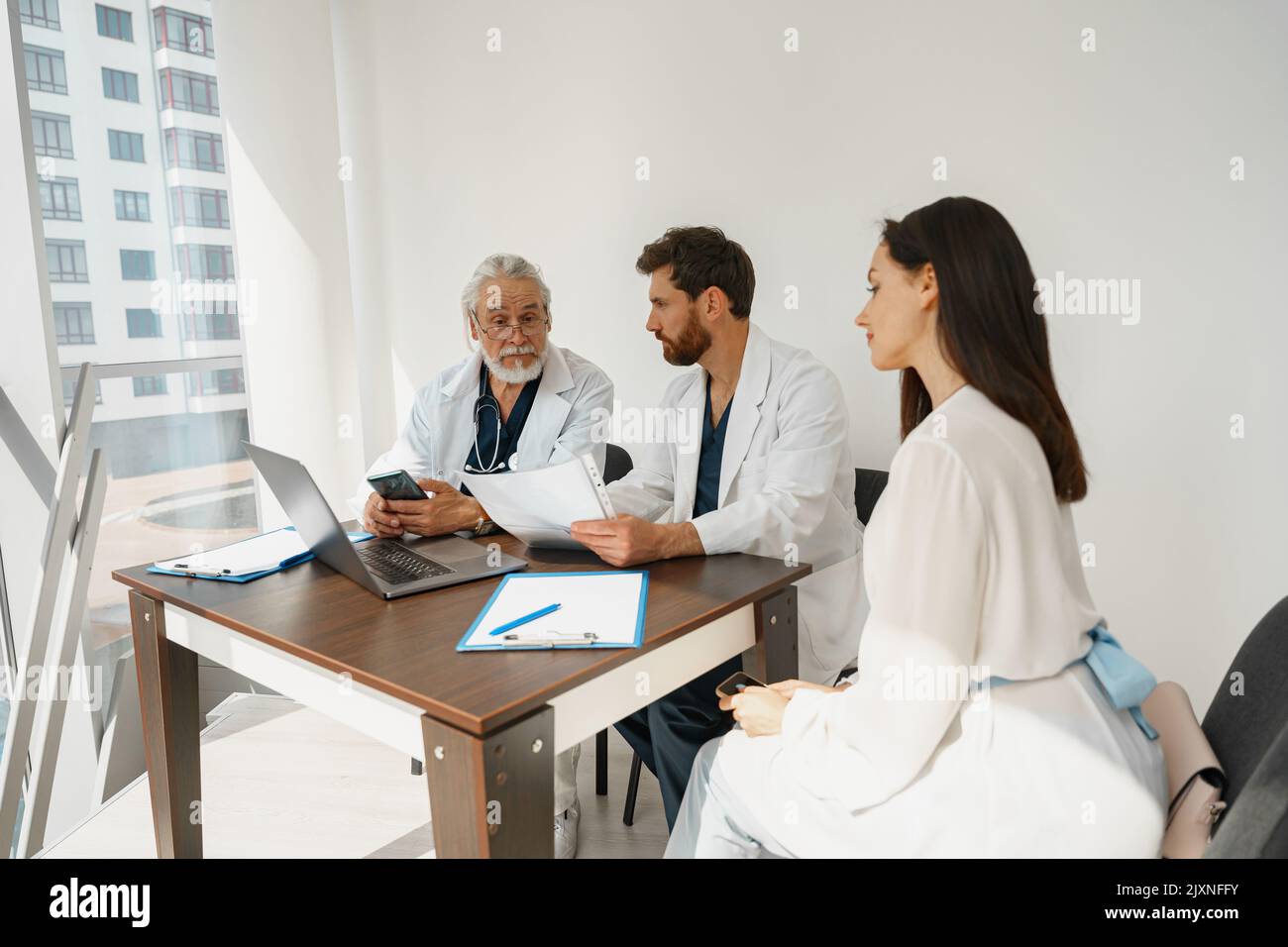 Due medici in uniforme bianca consultano la paziente femminile durante un incontro in clinica medica privata Foto Stock