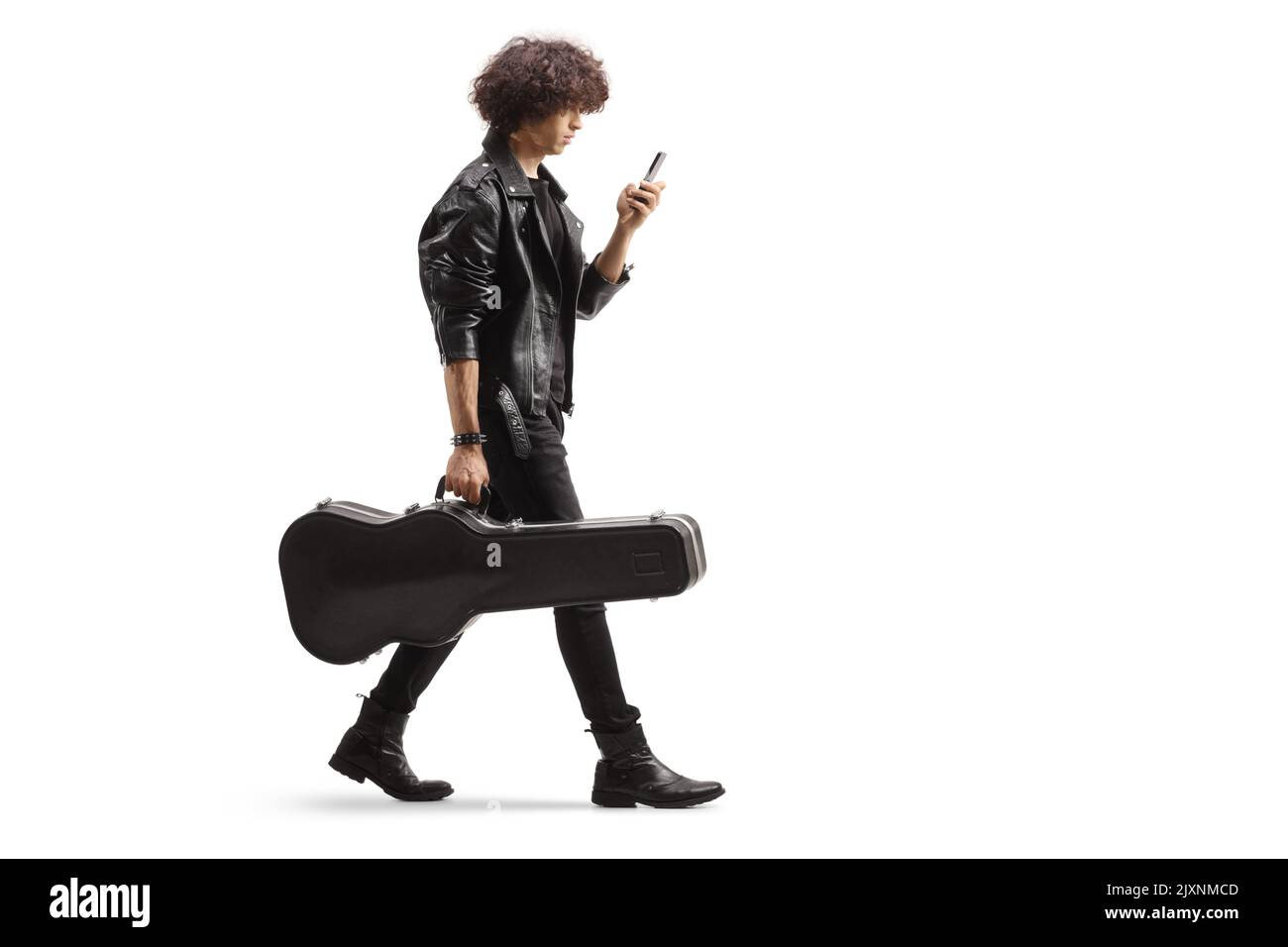 Profilo completo di un giovane musicista che porta una custodia per chitarra e utilizza uno smartphone isolato su sfondo bianco Foto Stock