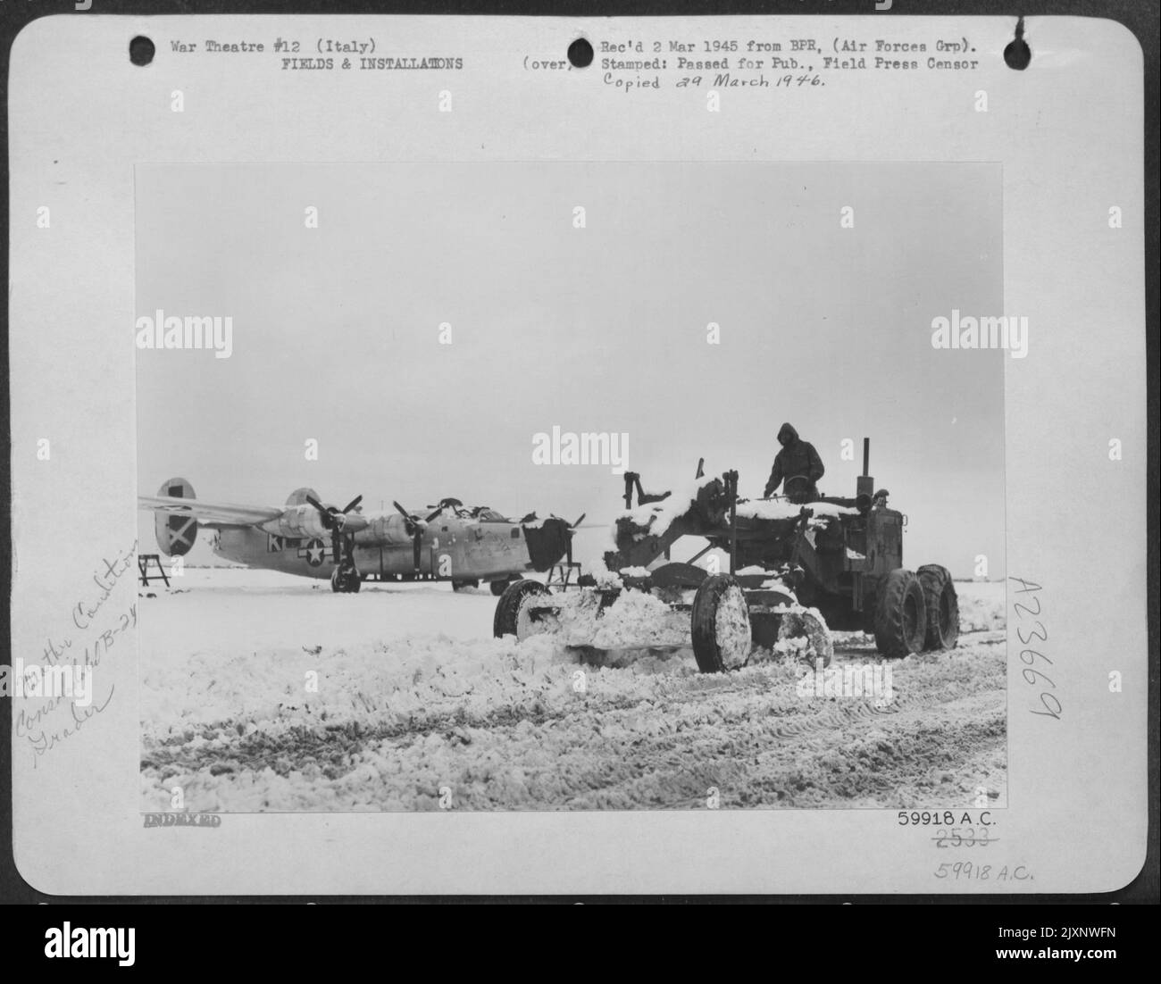 La neve forza Una battuta d'arresto nella guerra aerea. Il naso con cappuccio di questa AAF 15th coperta dalla neve Consolidated B-24 Liberator punti Glumly alla pista bloccata da drift e fango. Un Grader, presidiato da un ingegnere dell'aviazione, sta Clearing A Path at this Italian base in modo che Foto Stock