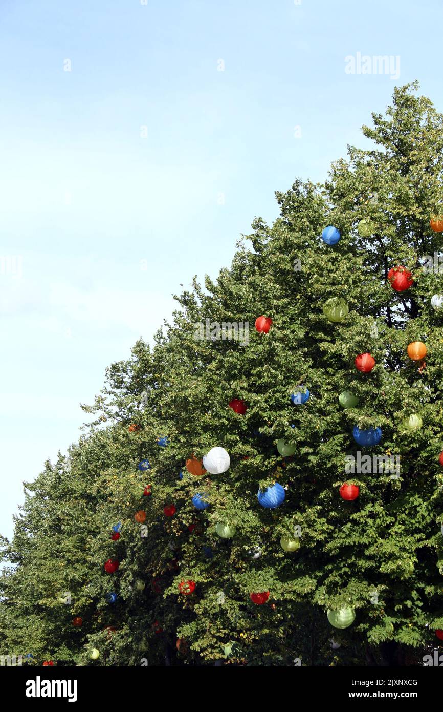 Lanterne colorate su un albero contro il cielo blu Foto Stock