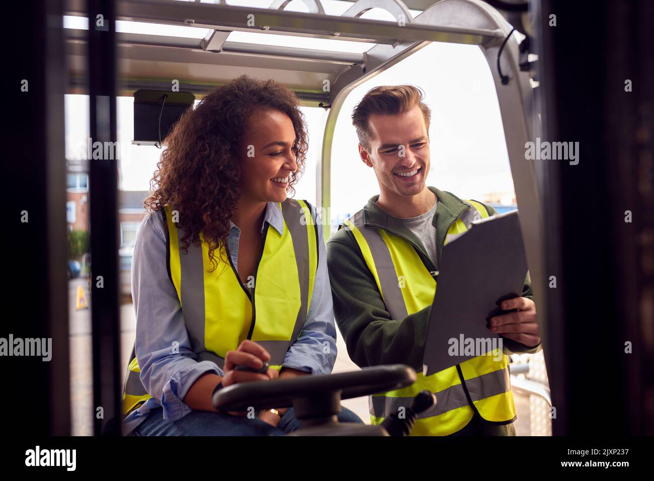 Personale maschile e femminile che aziona il carrello elevatore a forche nel magazzino moderno Foto Stock