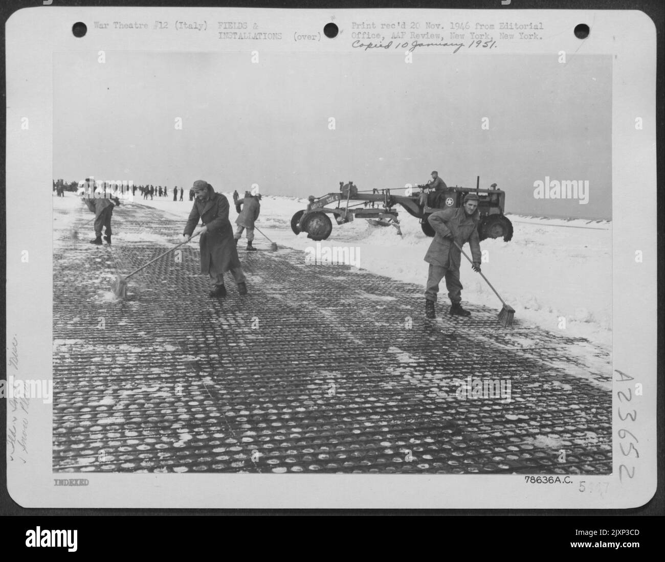 Ogni strumento disponibile è stato utilizzato per pulire la pista di un campo aereo al di sotto del livello del mare mantenuto da un battaglione di aviazione degli ingegneri in Italia dopo la sua prima esperienza con una tempesta di neve. Gli ingegneri lavorano qui con grandi scopa di paglia e un Foto Stock