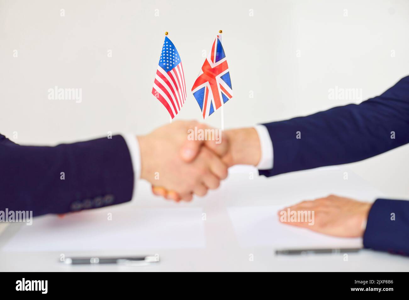 Stretta di mano di due uomini davanti alle bandiere della Gran Bretagna e degli Stati Uniti d'America Foto Stock