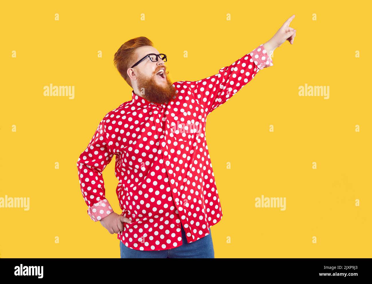 Allegro barbuto uomo punta in alto a destra angolo, isolato su sfondo arancione. Foto Stock