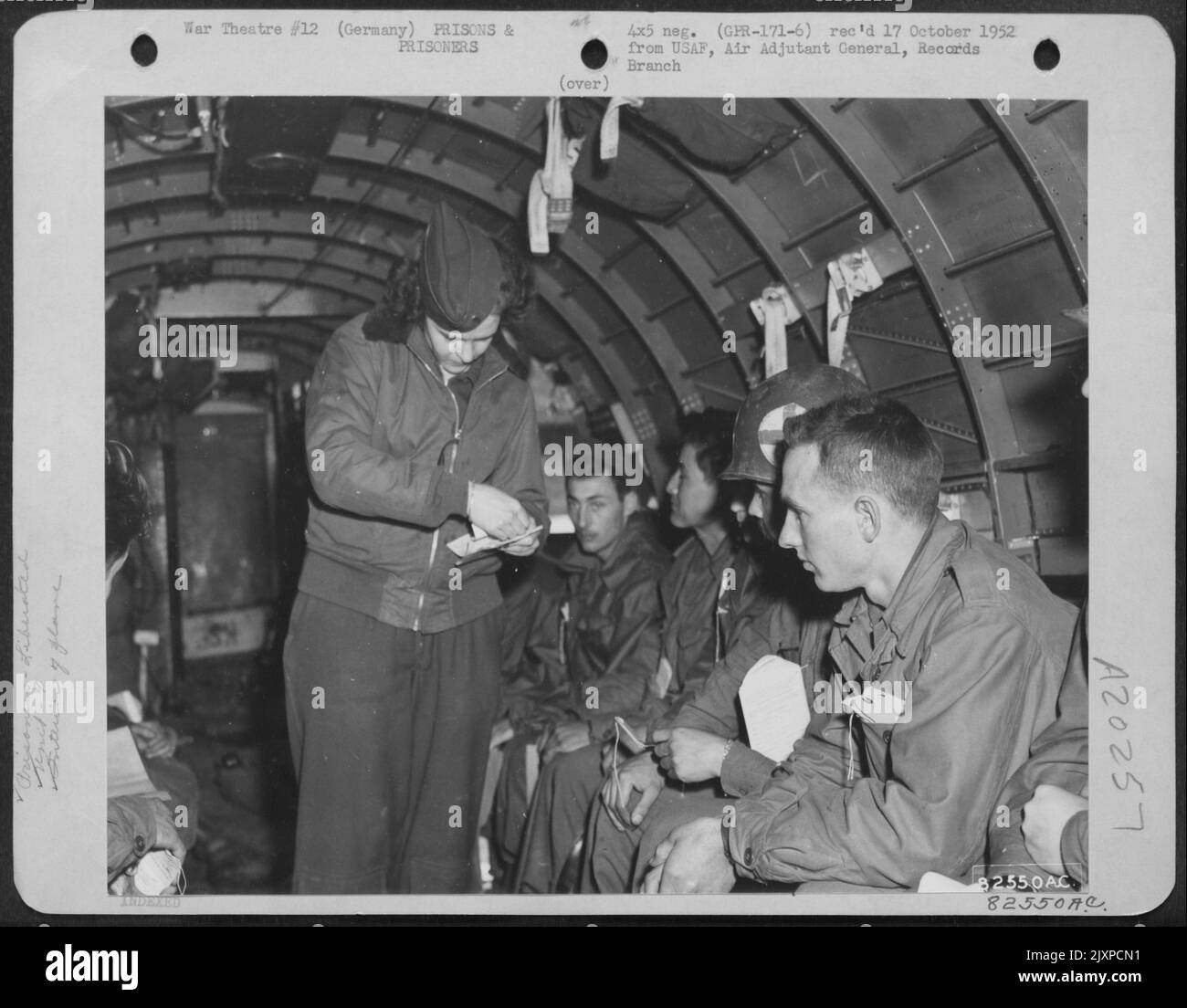 Un'infermiera di volo del comando portatore della truppa del 9th controlla le etichette di identificazione dei prigionieri di guerra liberati a bordo Di Un Douglas C-47. 27 aprile 1945. Foto Stock