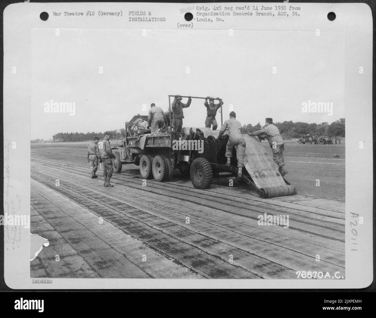 Gli uomini del Battaglione di Aviazione del 834Th costruiscono Una striscia di atterraggio a Buchschwabach, Germania, con il 'mat hessiano' usato per la superficie. Il tappetino, Una composizione simile a Tar-Paper, viene posato da camion caricati con rotoli da 200 piedi. UN 50%%%%%%%%% La sovrapposizione viene mantenuta a. Foto Stock