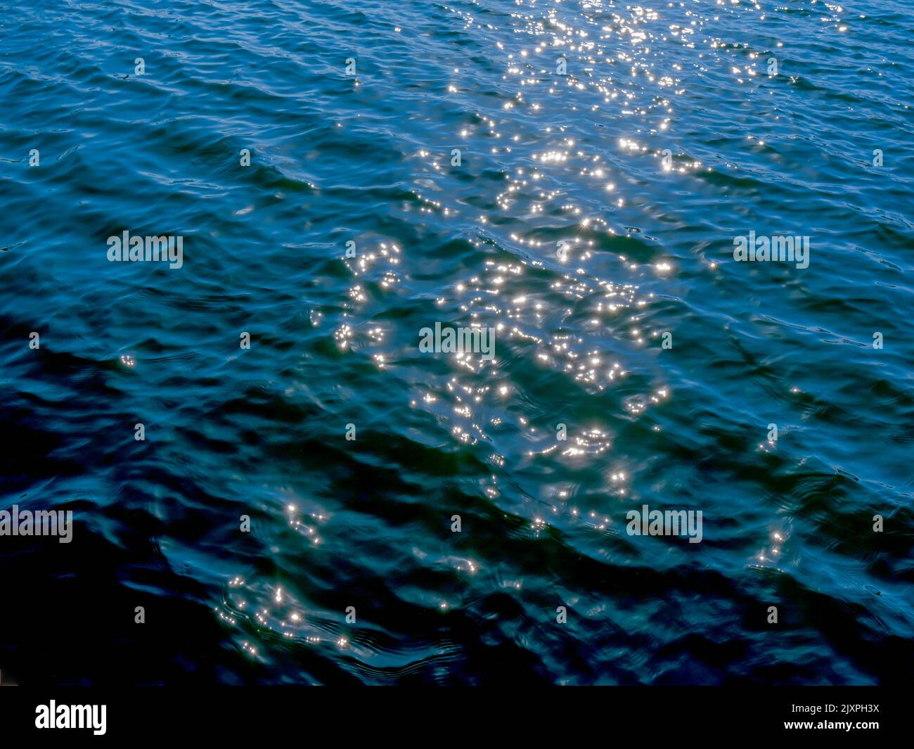 La luce del sole si illuminano sulle correnti di superficie del porto Foto Stock