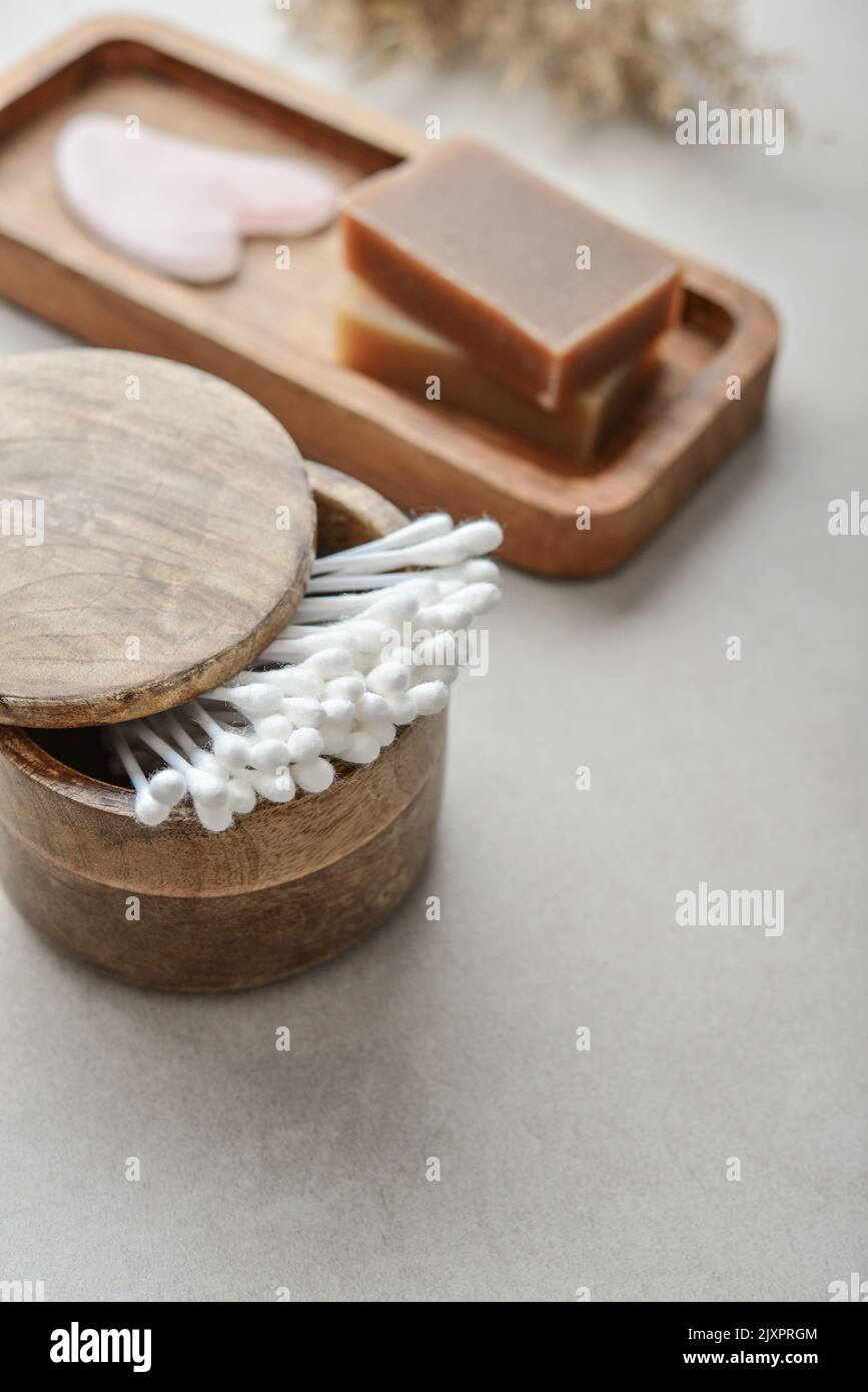Сotton germogli in scatola di legno con sapone su vassoio di legno su fondo di cemento chiaro Foto Stock