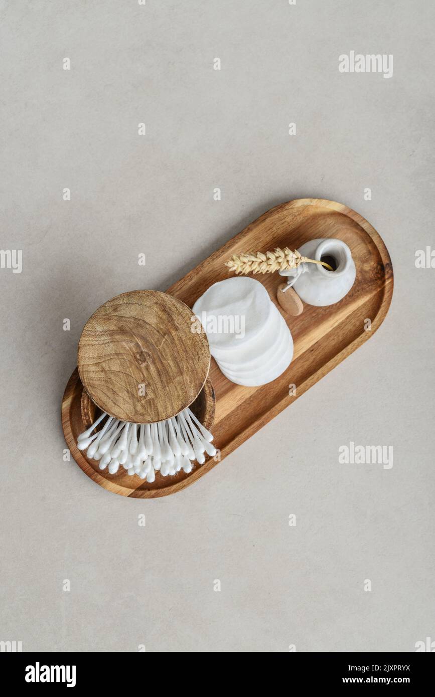 Boccioli di Сotton in scatola di legno con tamponi tondi in cotone facciale su vassoio di legno su fondo di cemento chiaro, vista dall'alto Foto Stock