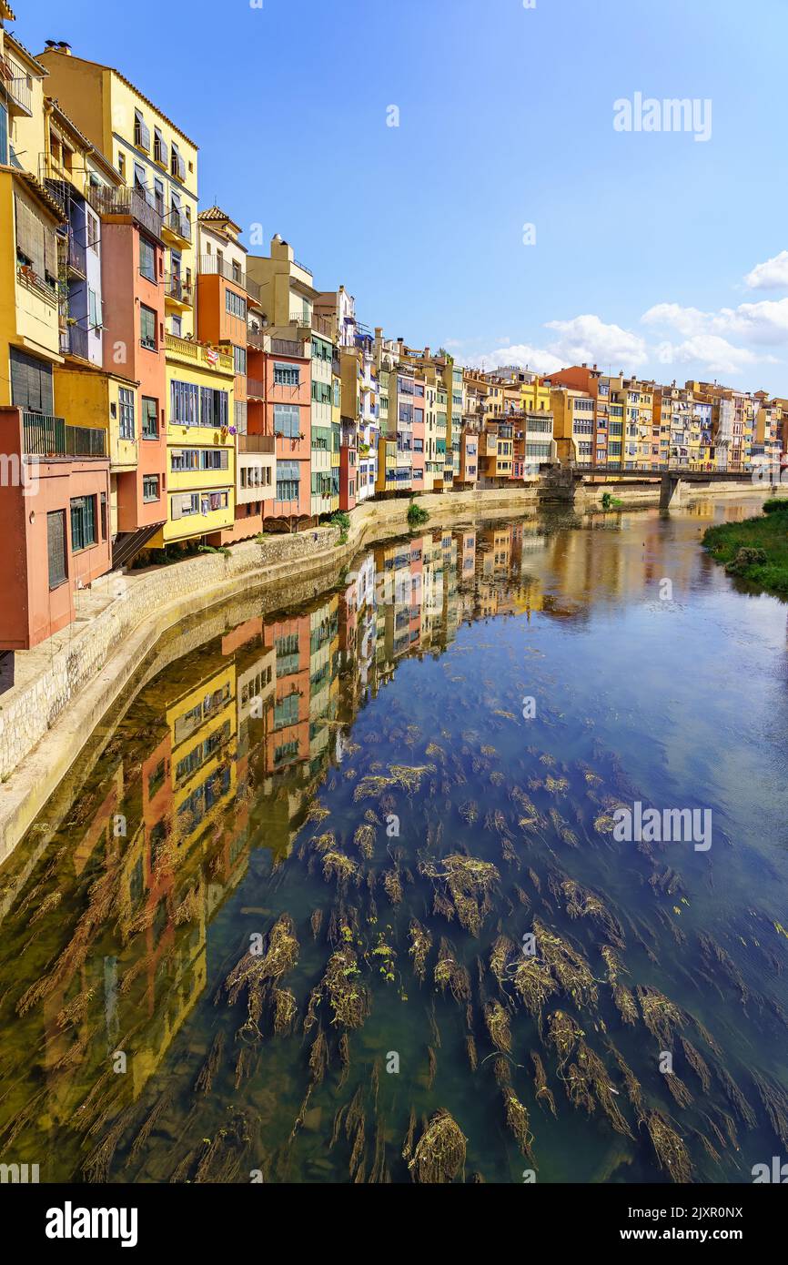 Case dai colori vivaci sulle rive del fiume e riflessione in acque calme in una giornata di sole, Girona, Catalogna. Foto Stock