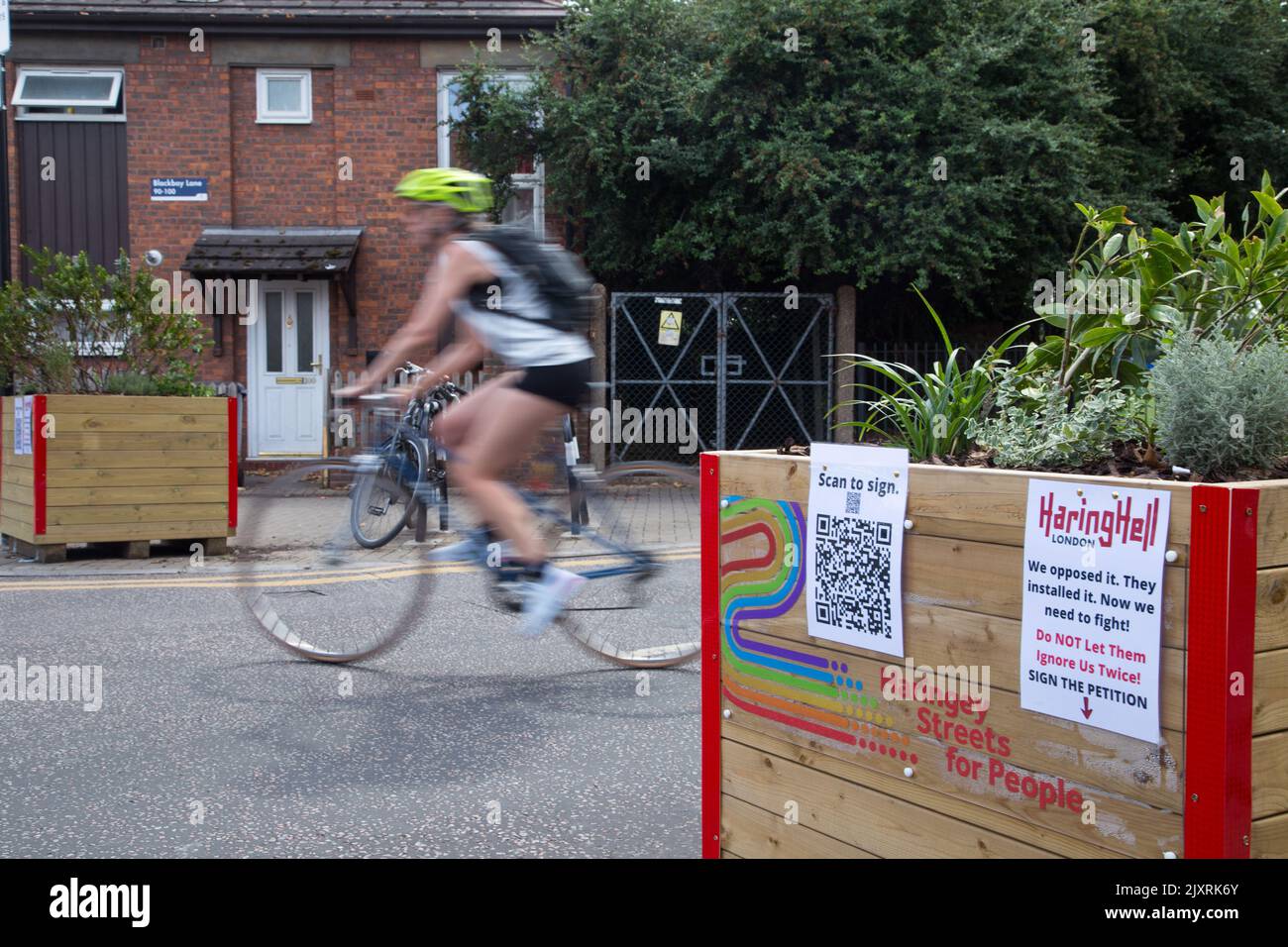 Un ciclista passa attraverso barriere che segnalano una controversa LTN (Low Traffic Neighbourhood) su Black Boy Lane nel quartiere di Haringey a Londra. Foto Stock
