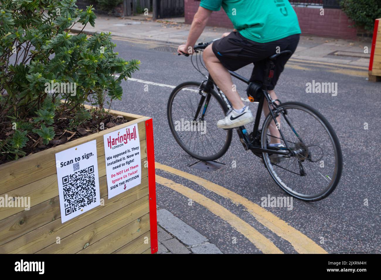 Un ciclista passa attraverso una barriera che segnala una nuova LTN (Low Traffic Neighbourhood) su Black Boy Lane nel quartiere di Haringey nel nord di Londra Foto Stock