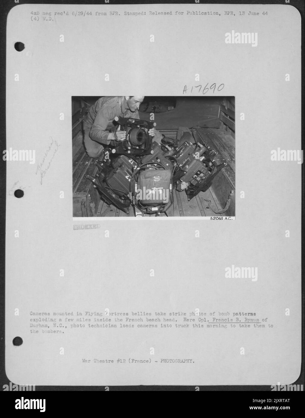 Le telecamere montate in Flying Fortress Bellies scattano foto di colpi di bombe che esplodono a pochi chilometri all'interno della testa della spiaggia francese. Qui CPL. Francis B. Bynum di Durham, N.C., il tecnico fotografico carica le macchine fotografiche nel camion questa mattina per portarle a. Foto Stock