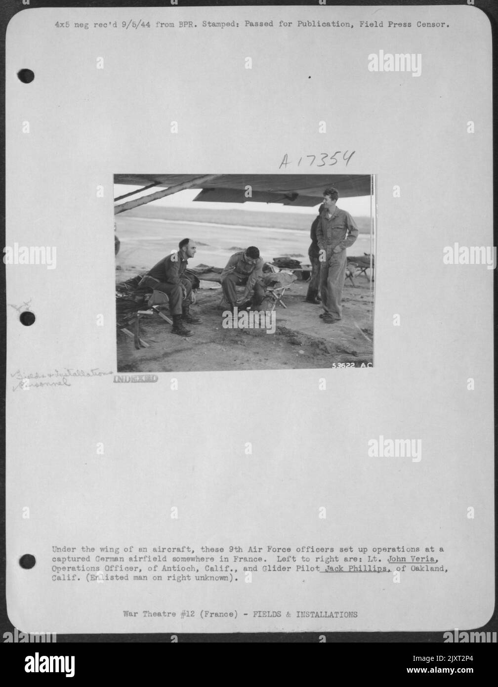 Sotto l'ala di un aereo, questi 9th ufficiali dell'aeronautica hanno istituito le operazioni in un campo aereo tedesco catturato da qualche parte in Francia. Da sinistra a destra sono: Il Lt. John Veria, Operations Officer, di Antioch, Calif., e il pilota Glider Jack Phillips, di Oakland Foto Stock