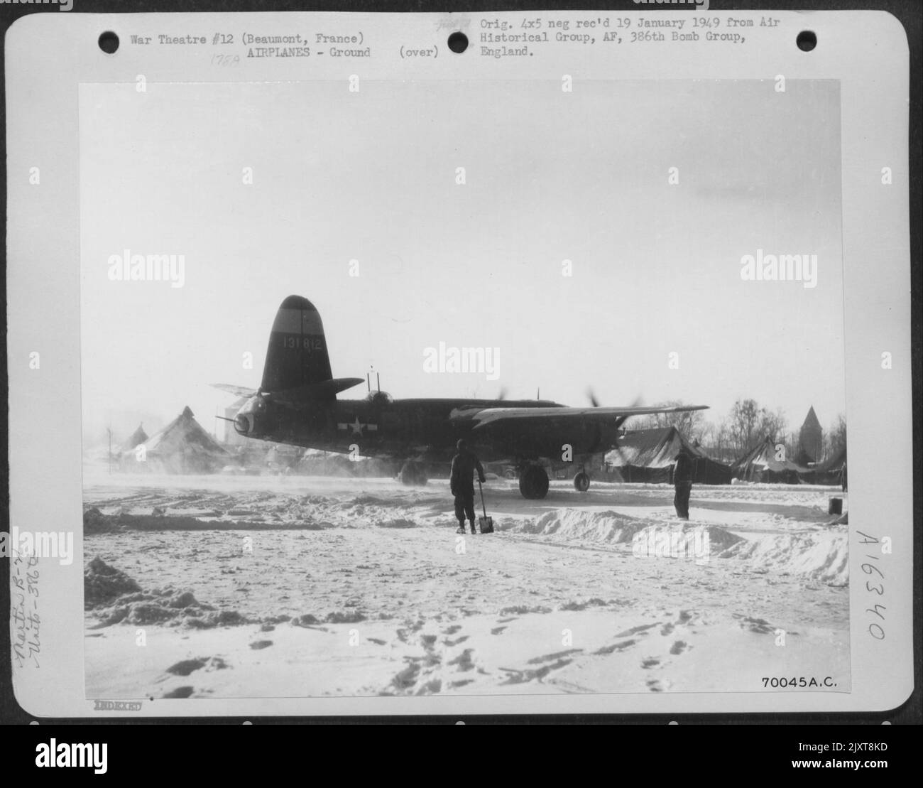 GIS sta ancora rimuovendo la neve dalla pista come pilota di Un Martin B-26 'Marauder' 'revs Up' ITS Engines alla base del Gruppo Bomb 386th a Beaumont, in Francia, il 14 gennaio 1945. Foto Stock