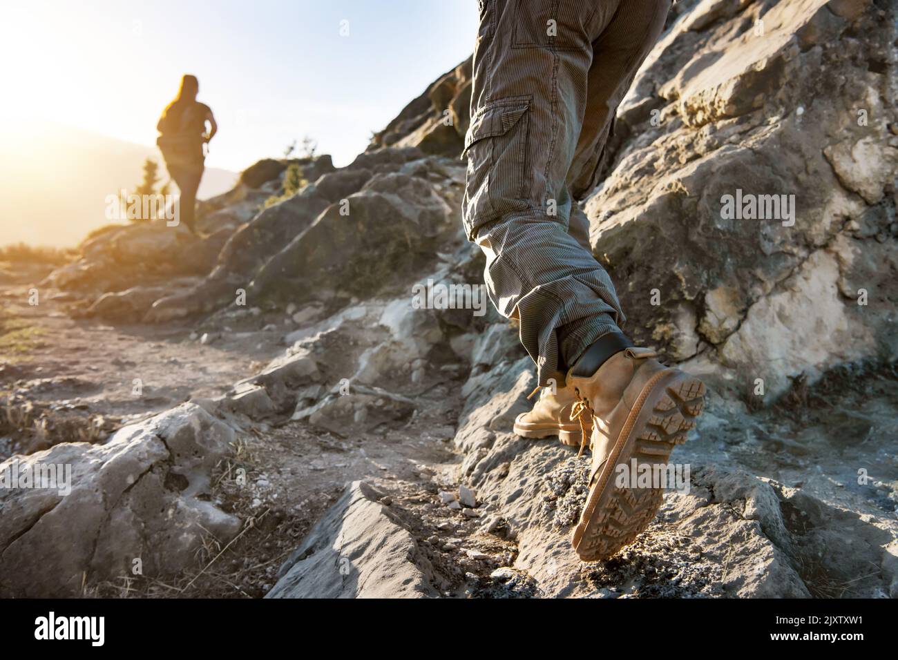 Foto in primo piano delle gambe maschio dell'escursionista e del turista femminile sfocato con zaino a piedi sul sentiero Foto Stock