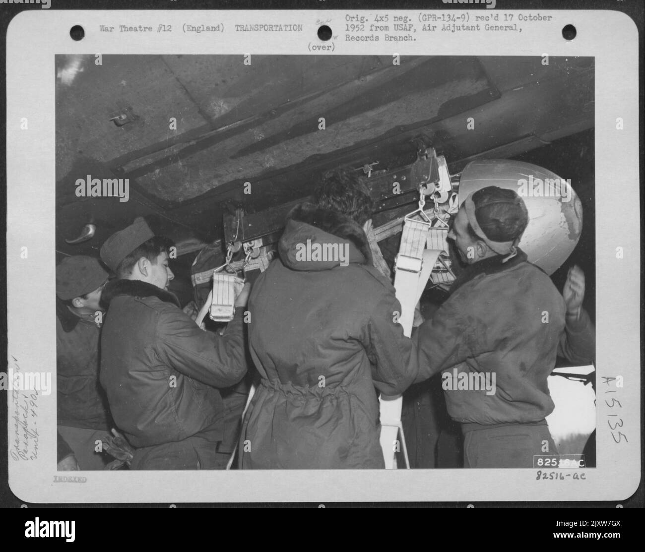 Men of the 490Th Qm Depot Co. Aumenta Un Parapack lineare in una rack su C-46 Curtiss 'Commando' Cargo Ship presso Una base di carrier truppa, da qualche parte in Inghilterra. 14 febbraio 1945. Foto Stock