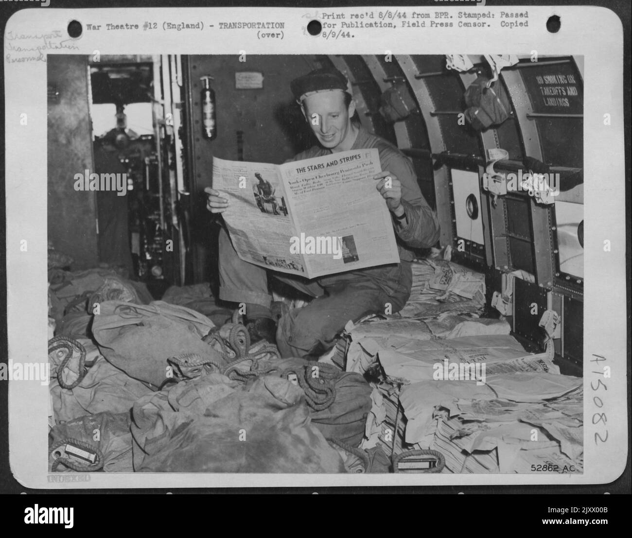 Capo equipaggio Sgt. W. H. Banks in un aereo di trasporto dell'aeronautica militare del 9th legge una copia del giornale dell'esercito delle stelle e delle strisce, mentre copie del giornale sono volate dall'Inghilterra alla Francia in Douglas C-53. Foto Stock