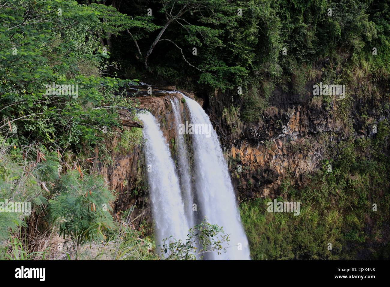 Tre cascate che scendono su una scogliera vulcanica circondata da una foresta pluviale a Wailua Falls a Kauai, Hawaii, USA Foto Stock