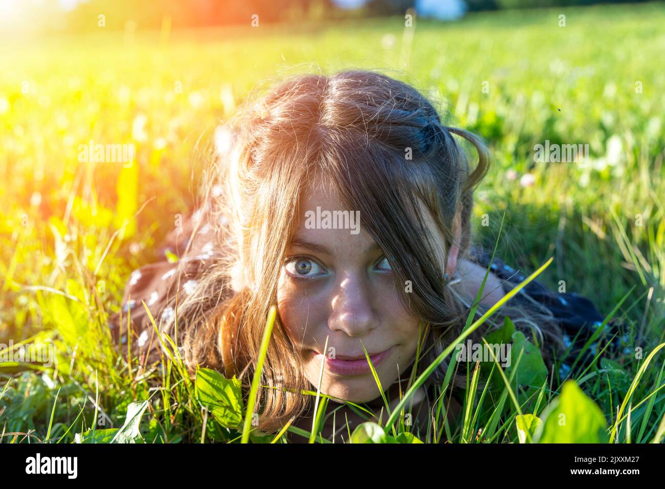 faccia di una ragazza sdraiata nell'erba primo piano. ricreazione esterna estiva Foto Stock