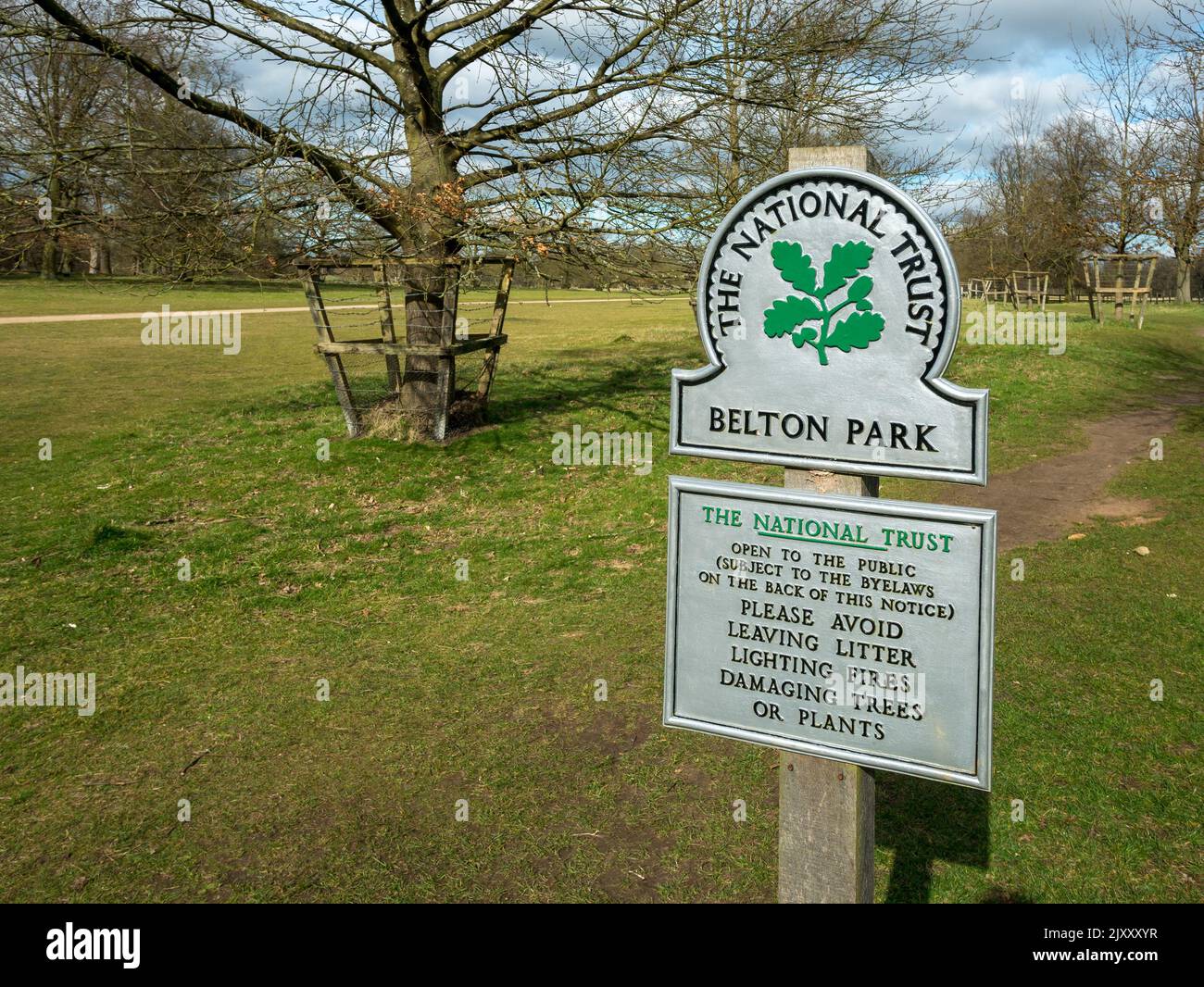 Nuovo, pulito, luminoso, dipinto di fresco, cartello National Trust all'ingresso di Belton Park con alberi e parco dietro, Grantham, Inghilterra, Regno Unito Foto Stock
