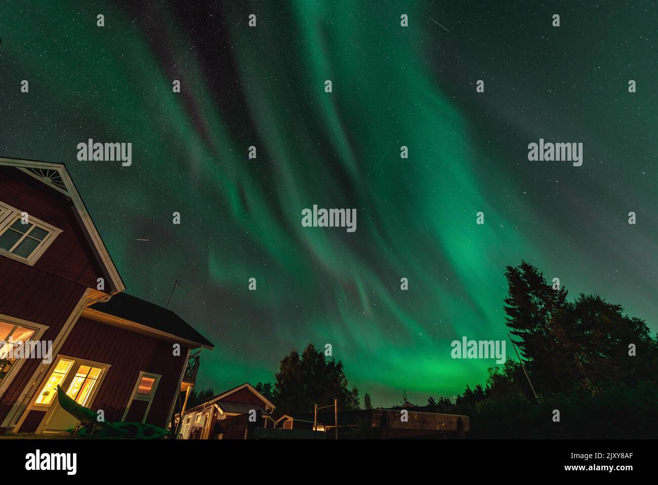 Ballare aurora borealis aurora in autunno sul cortile, parte della casa a parte. Aurora verde alta nel cielo. Umea città, Svezia, notte. Spazio di copia Foto Stock