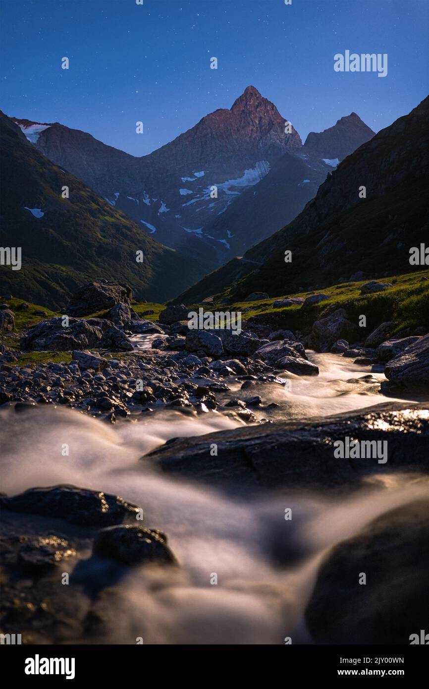 Lunga esposizione dell'acqua che scorre di un torrente nelle Alpi svizzere di notte Foto Stock