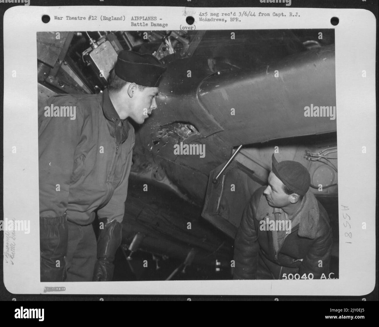 England-2nd Lt. Paul Keller, 4015 Brownsville Road, Pittsburg, Pa., ispeziona un buco proiettile di 20 mm sul bordo anteriore della radice dell'ala sinistra del suo aereo da combattimento Thunderbolt P-47. Nella foto è raffigurato il suo capo equipaggio, S/Sgt. Jack E. Morley, 1408 direzione est Foto Stock