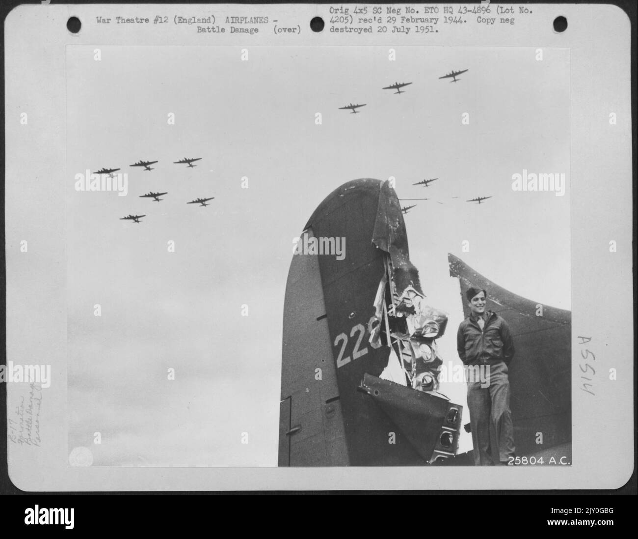 T/Sgt. Harris Goldberg di Brookline, Mass., Boeing B-17 codone, si trova accanto alla coda del suo aereo che è stato colpito da un fuoco di cannone di 20 mm. Durante una missione sul territorio nemico. Una formazione del Boeing B-17s può essere vista volare sopra. Thurleigh Foto Stock