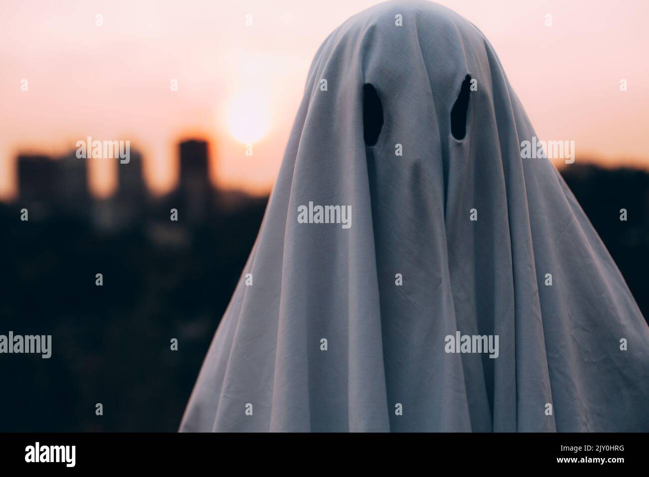 Primo piano ritratto di fantasma spettrale in piedi contro la città serale durante Halloween Foto Stock