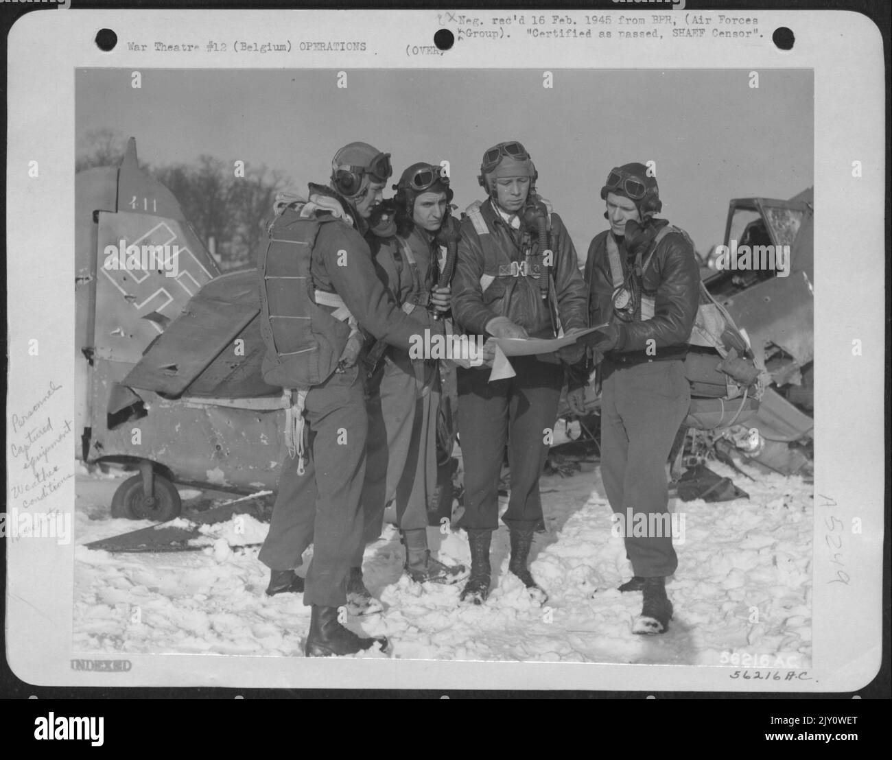 Il col. Ray J. Stecker, Hazelton, Pa., comandante del gruppo di combattenti-bombardieri del 365th discutono un piano di volo con tre dei suoi comandanti dello squadrone. Sullo sfondo c'è un FW-190 distrutto. Da sinistra a destra: L. col. George R. Brooking, Livingston, Month. Foto Stock
