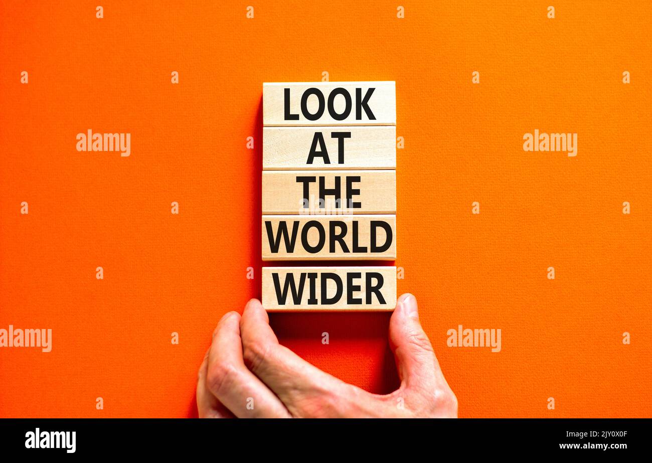 Guarda il simbolo del mondo. Le parole di concetto guardano il mondo più in generale su blocchi di legno su uno sfondo arancione bello. Mano uomo d'affari. Business An Foto Stock