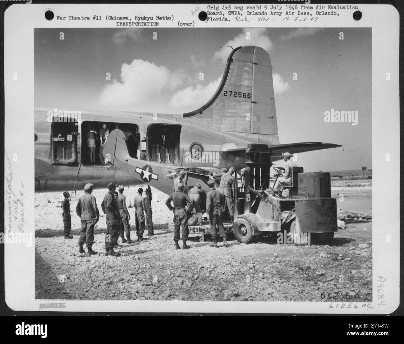 11 personale aereo che passa attraverso il lavoro estremamente difficile di caricare Un aereo di collegamento L-4 Piper su un comando di trasporto aereo Douglas C-54 'Skymaster'. Kadena Airstrip, Okinawa, Ryukyu Rett. 30 agosto 1945. Foto Stock