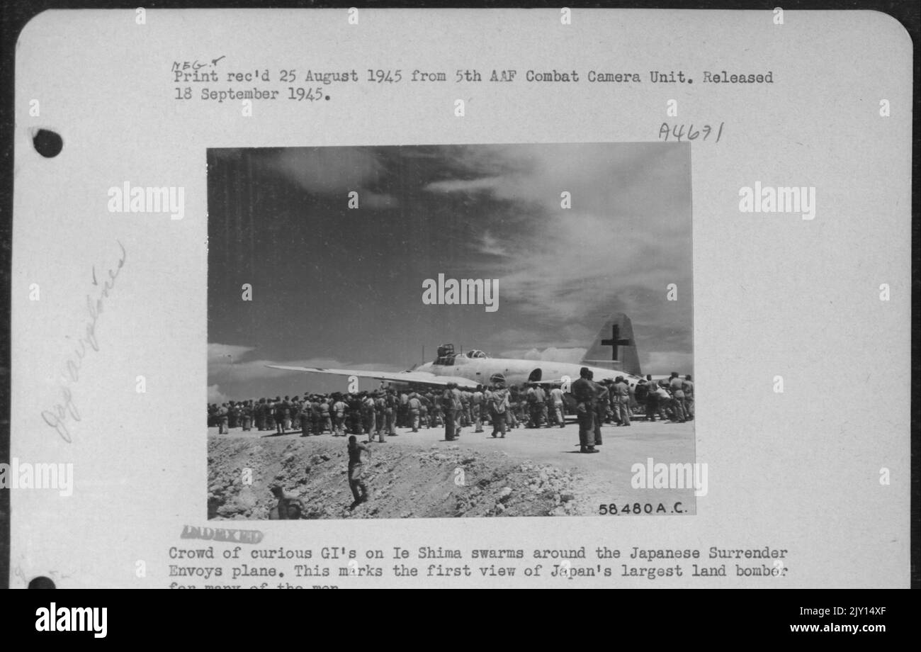 Folla di curiosi Gi's su ie Shima sciami intorno al giapponese resa Envoys aereo. Questo segna la prima veduta del più grande Land Bomber del Giappone per molti uomini. Foto Stock