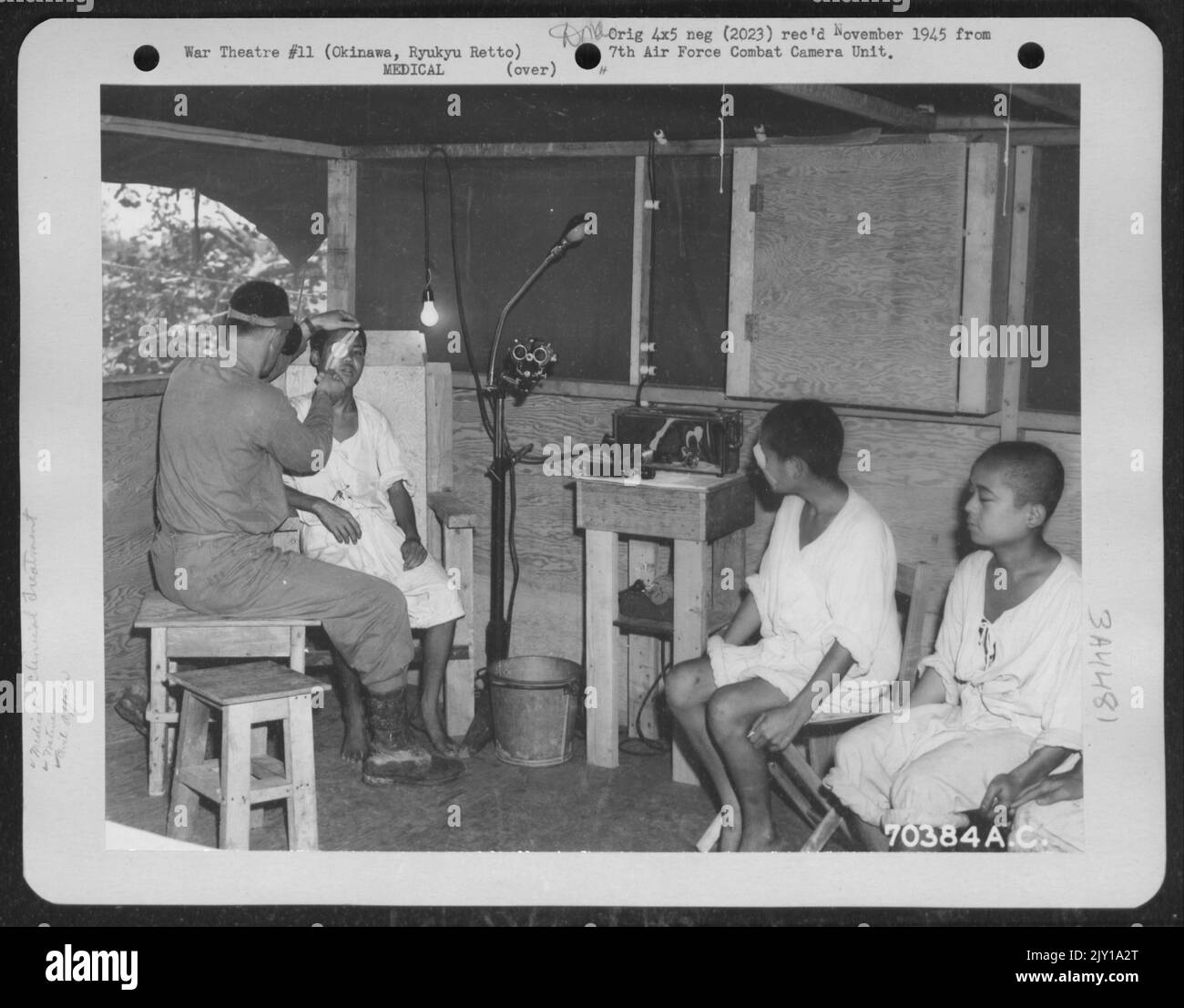 Un nativo di Okinawan che soffre di un'infezione oculare è trattato nella clinica di orecchio, occhio, naso e gola dell'American Military Government Hospital di Okinawa, Ryukyu Retto. Alcuni dei suoi connazionali attendono il loro turno per l'attenzione medica. 15 giugno 194 Foto Stock