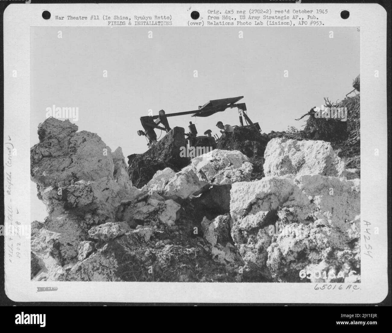 Membro del 1902Nd Engineer Aviation Battalion Operating Bulldozer che fa derapare enormi rocce da bordo di Coral Pit appena aperto su Shima, Ryukyu Retto. Foto Stock