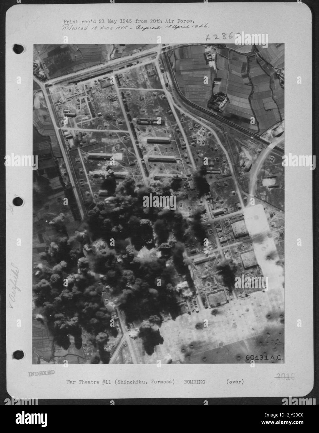 Bombe da Una formazione di Boeing B-29 Superfortezze esplodere tra gli edifici a Shinchiku Airdrome, Isola di Formosa. Foto Stock