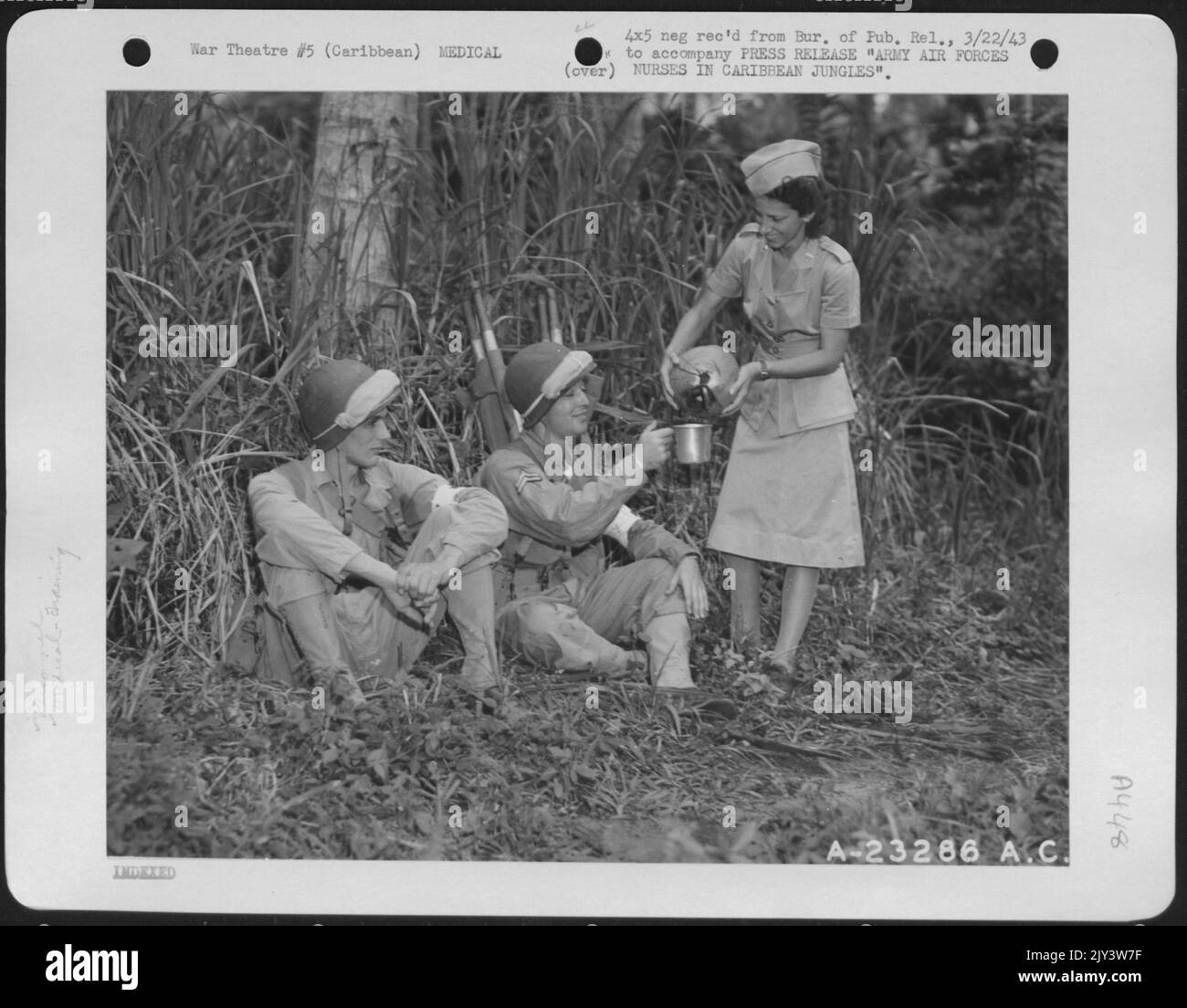 Gli ufficiali del corpo delle infermiere dell'esercito si familiarizzano con le giungle lussureggianti. Qui, il Lt. Rosemary Laidacker, Muncey, Pal, dà PFC. Joseph Grant, Repubblica, Pa. E CPL. Edward C. White, Des Moines, Iowa, una bevanda fresca nella giungla. Foto Stock