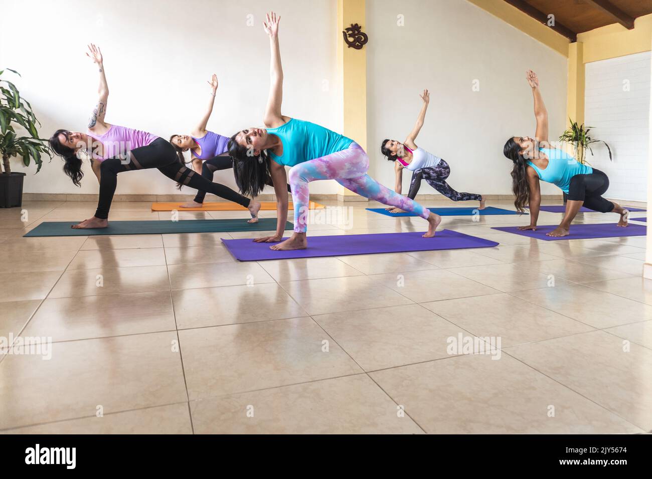 Donne in una stanza di yoga che praticano Parsvakonasana, posa ad angolo laterale esteso Foto Stock