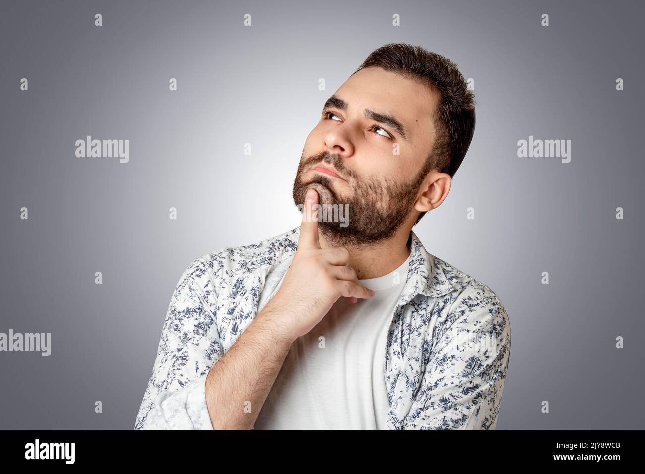 Una persona che pensa e guarda in su, mettendo la mano al suo volto, sfondo isolato Foto Stock