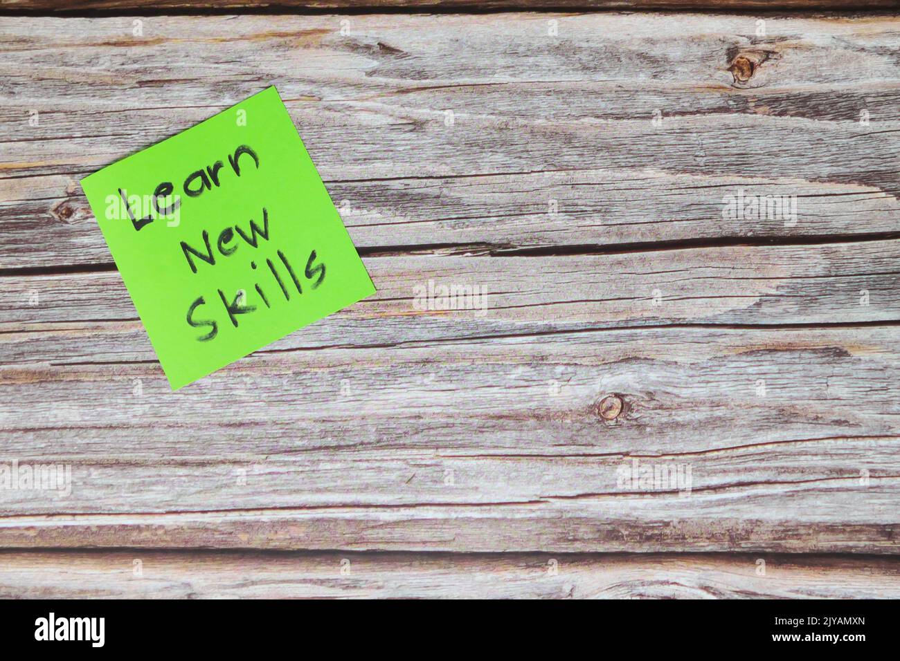 Imparare nuove competenze per il miglioramento di sé e il concetto di sviluppo personale. Promemoria adesivo verde su sfondo di legno con spazio per le copie. Foto Stock