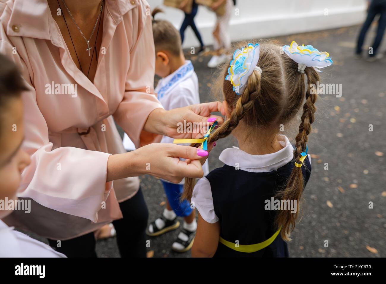 Profondità di campo bassa (fuoco selettivo) dettagli con la bandiera Ucraina prua nei capelli di una ragazza scolastica. Foto Stock